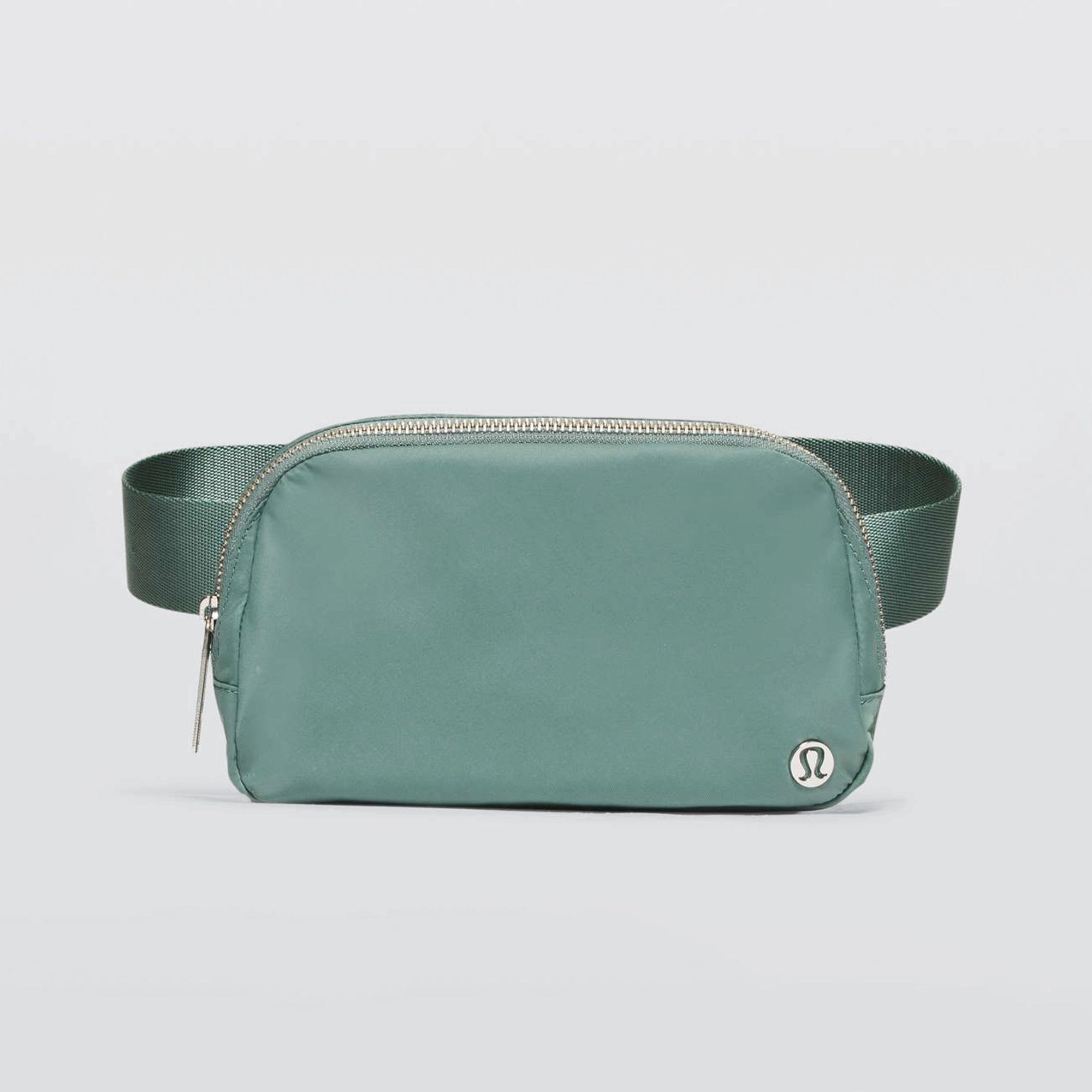 A greyish turquoise Lululemon Everywhere Belt Bag 1L with a zipper closure and an adjustable strap, displayed against a white background.