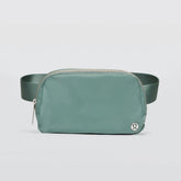 A greyish turquoise Lululemon Everywhere Belt Bag 1L with a zipper closure and an adjustable strap, displayed against a white background.